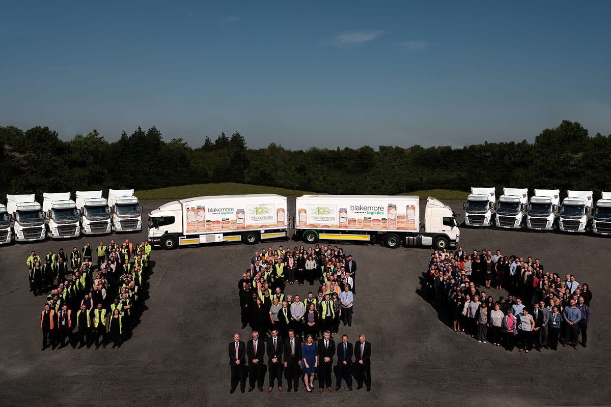 AFBlakemore team assembled on the logistics forecourt, arranged in a 100 figure surrounded by AFBlakemore branded trucks. An image to celebrate the 100 Years of AFBlakemore. 