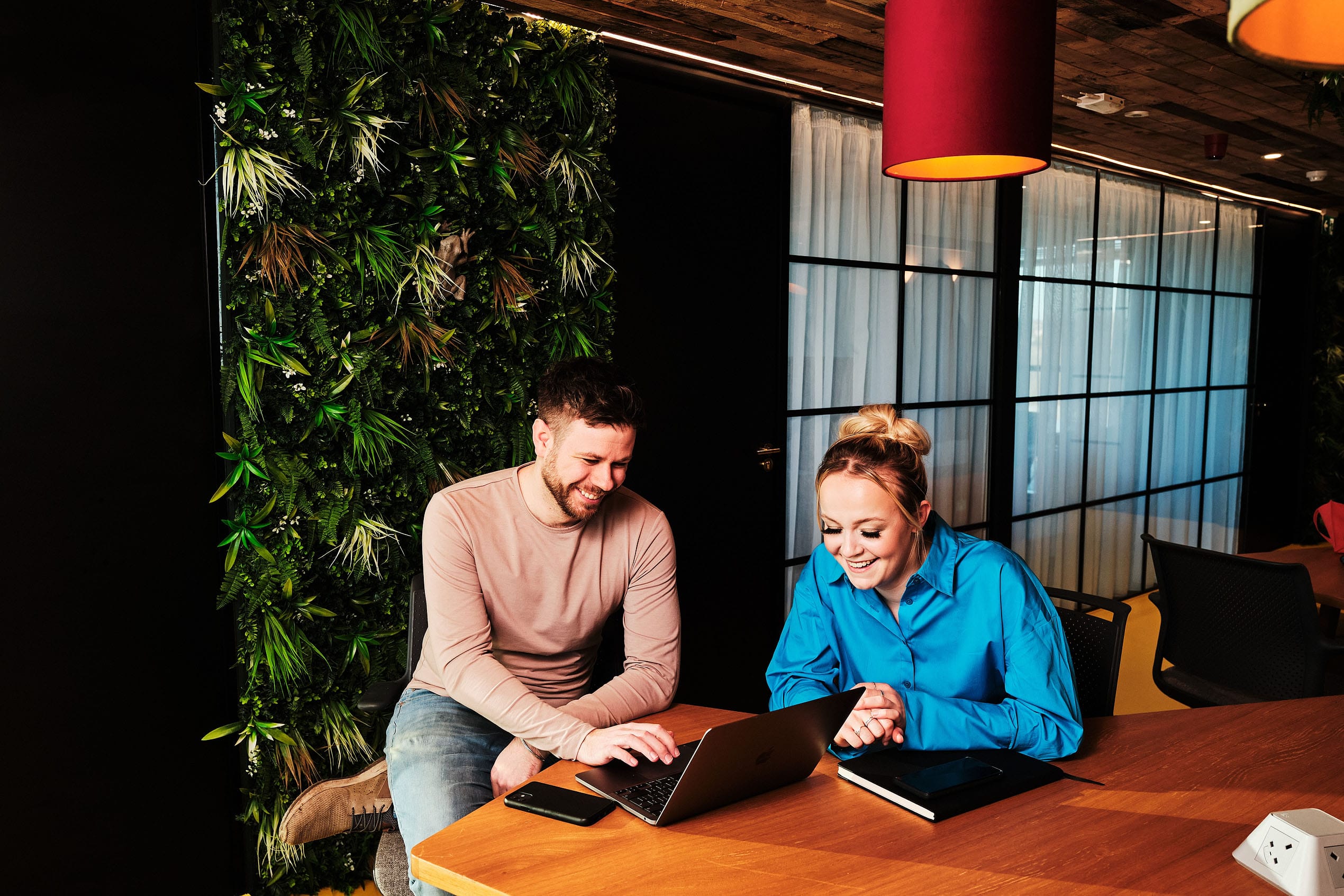Creative brand photography portrait with Thalia and Tom from Offiss and Penrose Design discussing their brand development over a laptop in the Offiss Cannock shared office space.